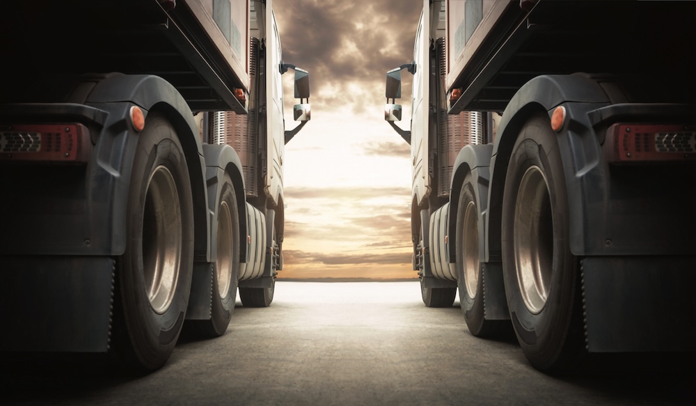 Two 18-wheelers side by side at sunset. New federal regulations would prevent deadly truck accidents.