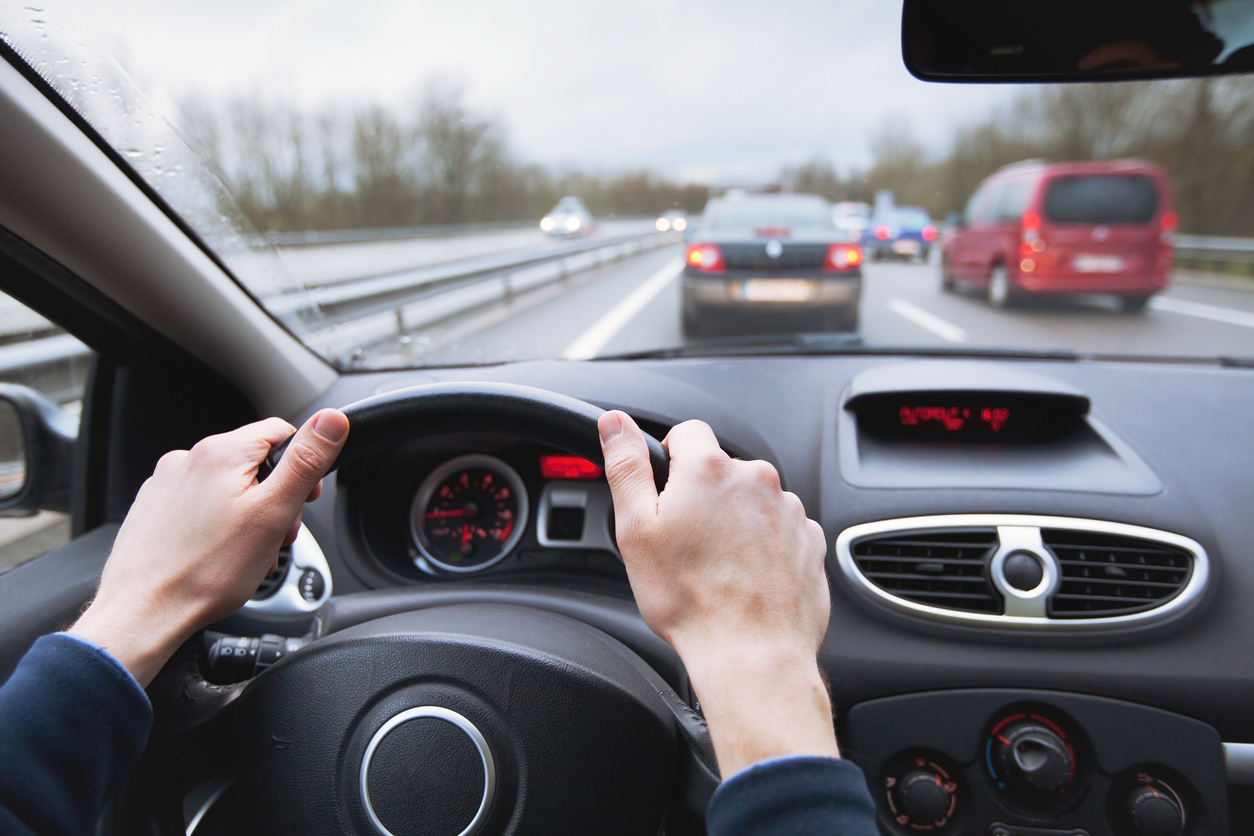 Driving safely on winter highways in Texas with light rain and cars breaking ahead.