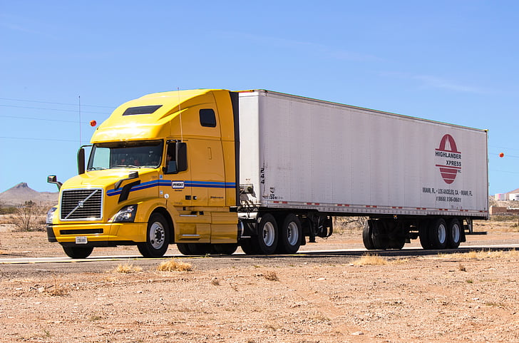 Yellow and white 18-wheeler on a desert road.